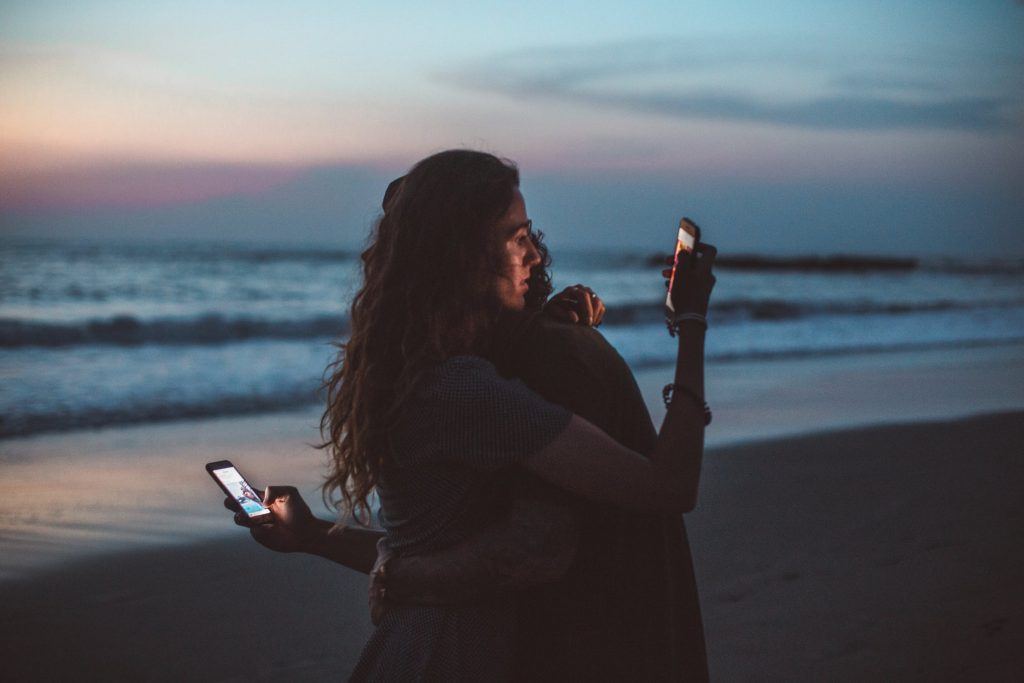 couple-hugging-on-phones-smartphone-addiction-signs-symptoms-tips-expat-nest